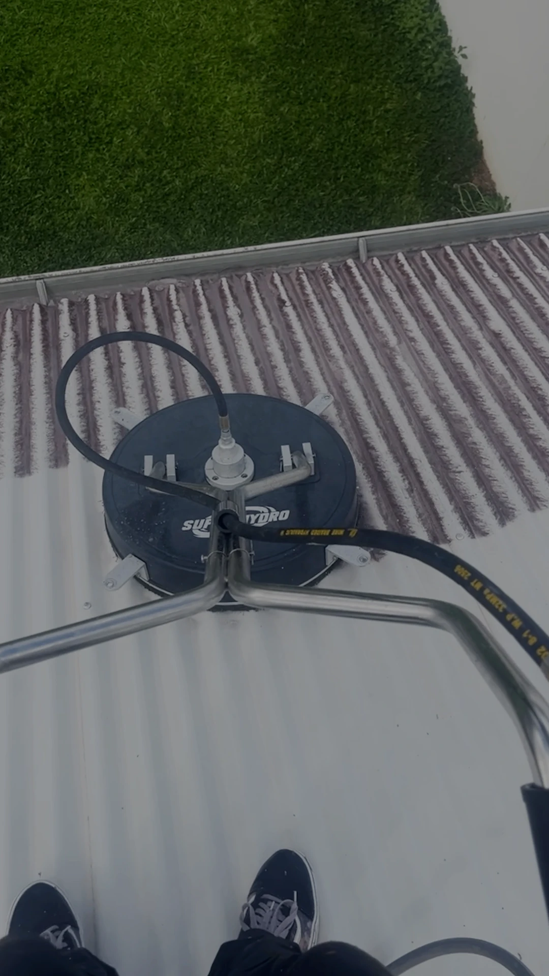Surface cleaner removing grime from a corrugated metal roof